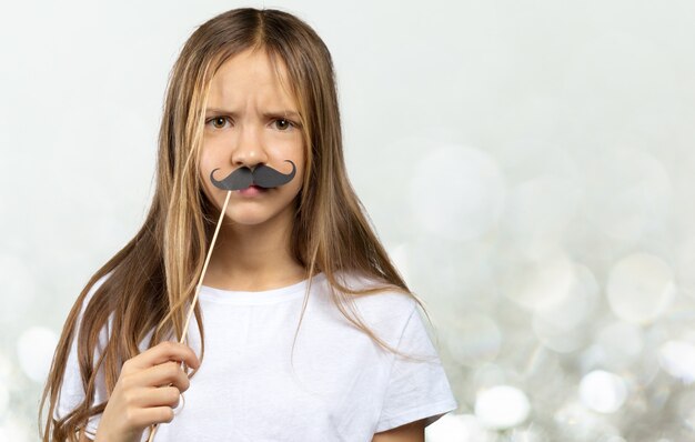 Bambina adorabile in a con la carta divertente dei puntelli della foto. Ragazzo felice