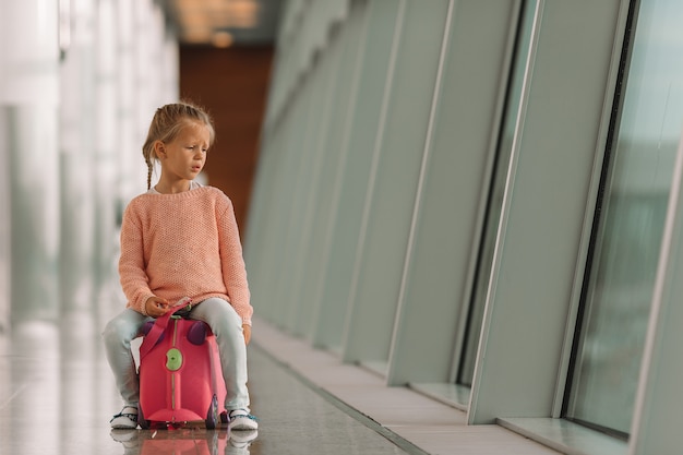 Bambina adorabile in aeroporto con l'imbarco aspettante dei suoi bagagli