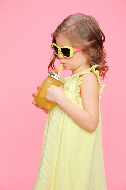 Bambina adorabile in attrezzatura di estate con la bevanda