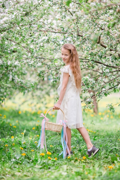 Bambina adorabile nel giardino delle mele di fioritura il bello giorno di molla