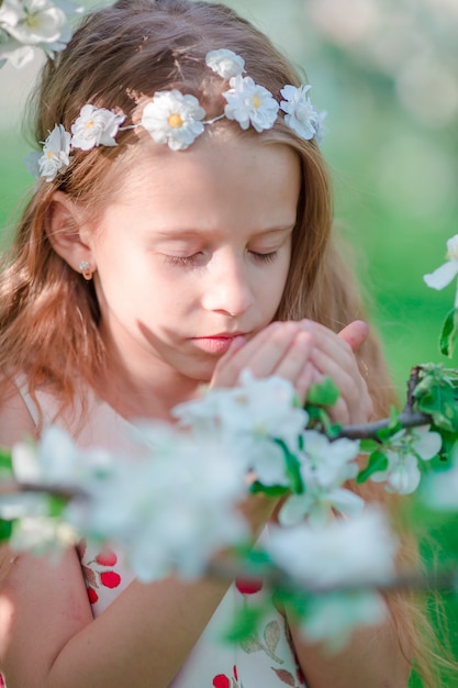 Bambina adorabile nel giardino di fioritura di melo il giorno di molla