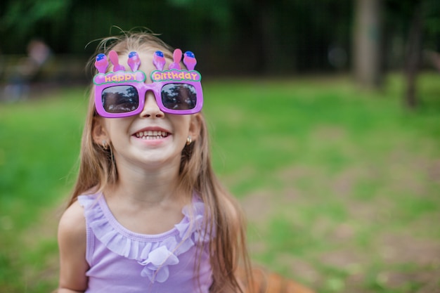 Bambina adorabile nel sorridere di vetro di buon compleanno all'aperto