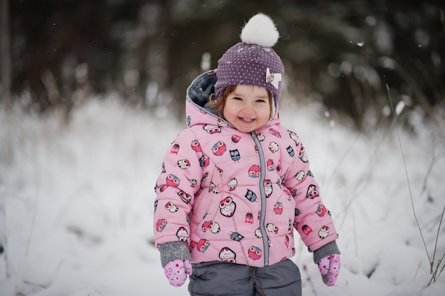 Bambina al giorno d'inverno. Camminare nel parco in una giornata fredda con la neve.