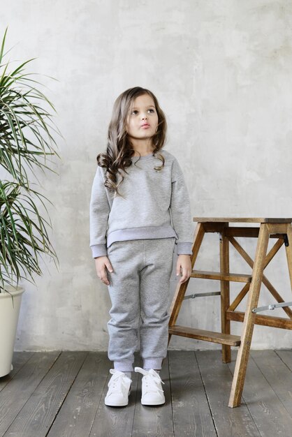 Bambina alla moda in un vestito grigio