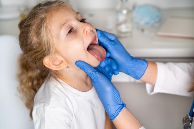 Bambina alla reception presso il medico otorinolaringoiatra esame della cavità orale nella gola del bambino