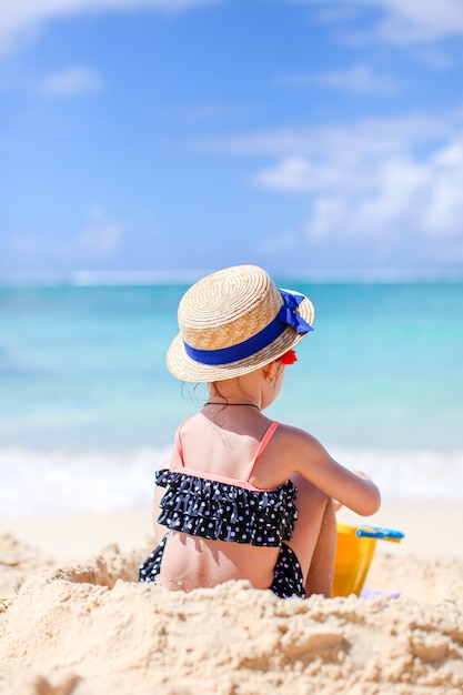 Bambina alla spiaggia bianca tropicale che fa il castello di sabbia