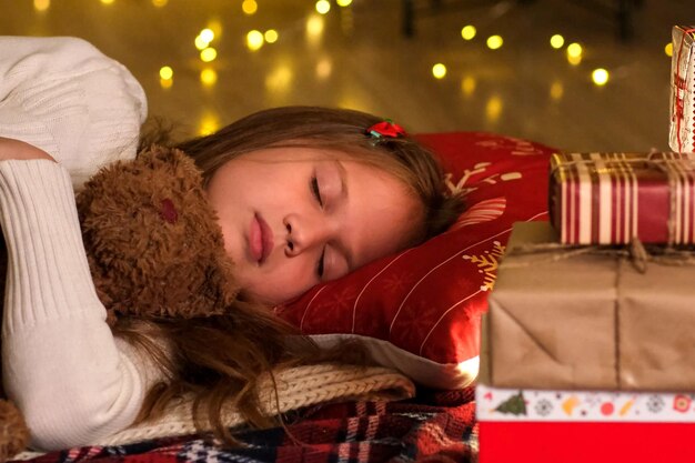 Bambina alla vigilia di Natale che dorme in attesa del regalo per le vacanze da Babbo Natale