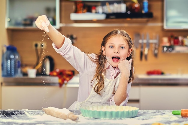 Bambina allegra che cucina pasta in cucina.