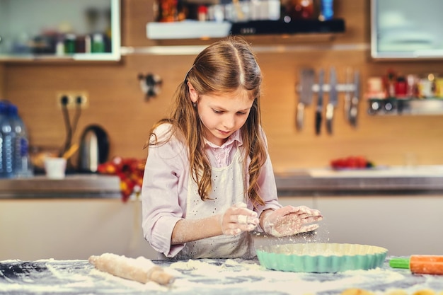 Bambina allegra che cucina pasta in cucina.