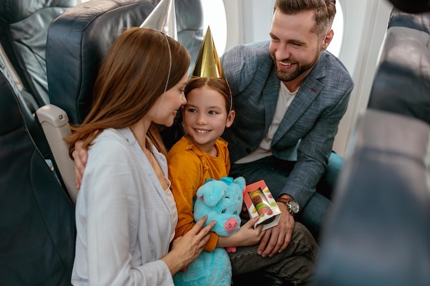 Bambina allegra che festeggia il compleanno con i genitori in aereo