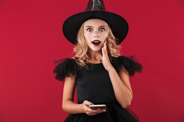 Bambina allegra che indossa il costume da strega di Halloween in piedi