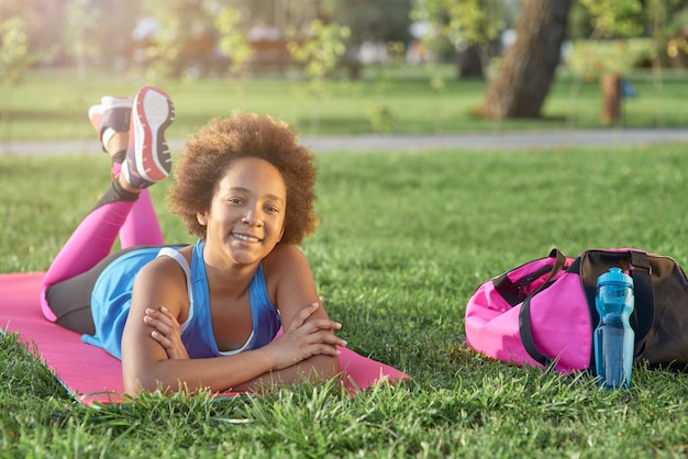 Bambina allegra che si trova sulla stuoia di yoga all'aperto