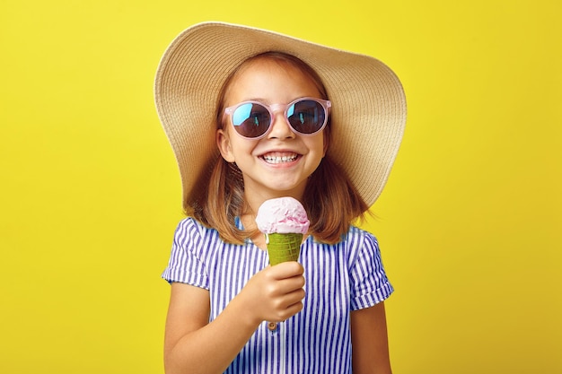 Bambina allegra con gelato su sfondo giallo isolato