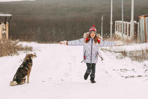 Bambina allegra felice che si diverte nella foresta in una giornata invernale. il bambino gioca con la neve.