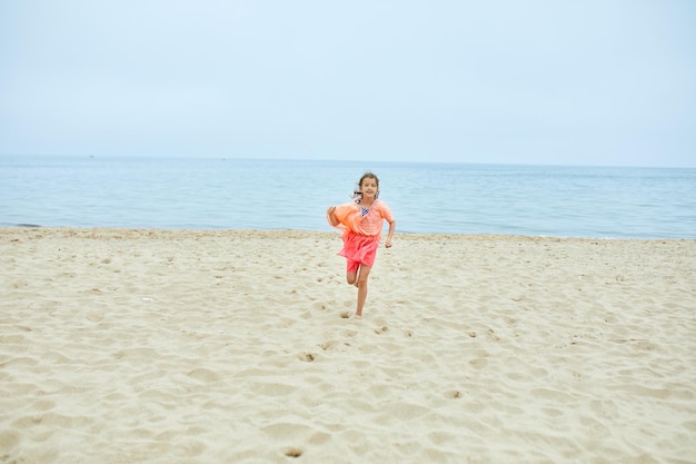 Bambina allegra felice correre sulla spiaggia