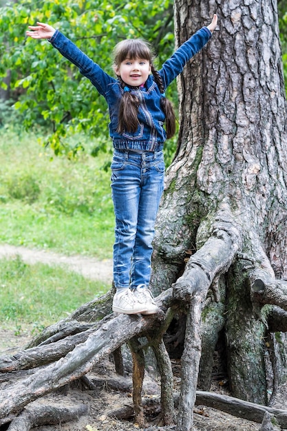 Bambina allegra in bilico sulle radici di un albero