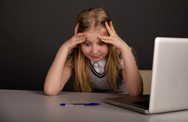 Bambina annoiata e stanca seduta davanti al computer Concetto di malessere