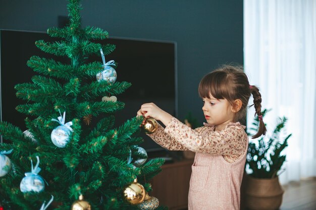 Bambina appeso ornamenti su un albero di Natale