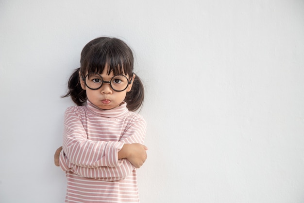 Bambina arrabbiata su sfondo bianco, segno e concetto di gesto