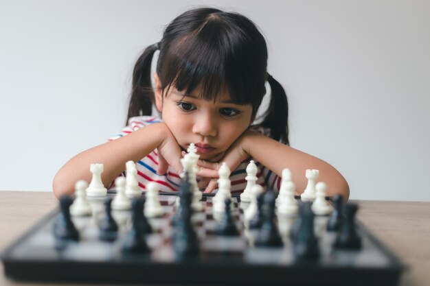 Bambina asiatica che gioca a scacchi a casa un gioco di scacchi