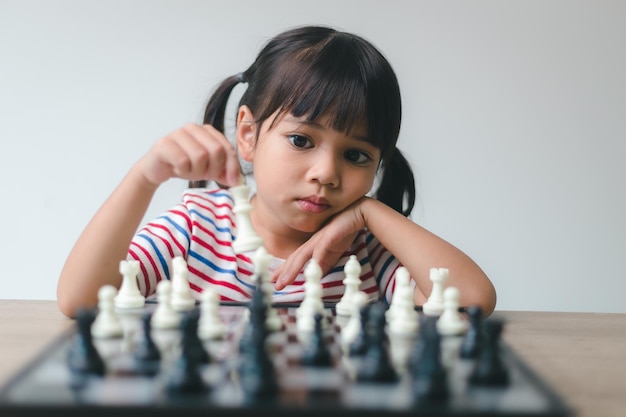 Bambina asiatica che gioca a scacchi a casa un gioco di scacchi