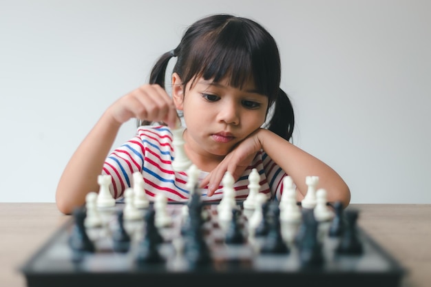 Bambina asiatica che gioca a scacchi a casa un gioco di scacchi