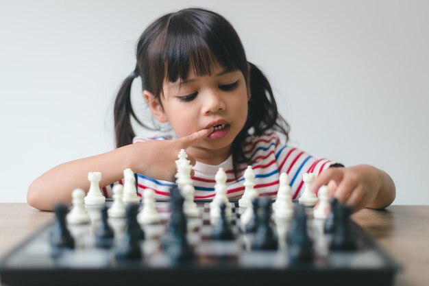 Bambina asiatica che gioca a scacchi a casa un gioco di scacchi