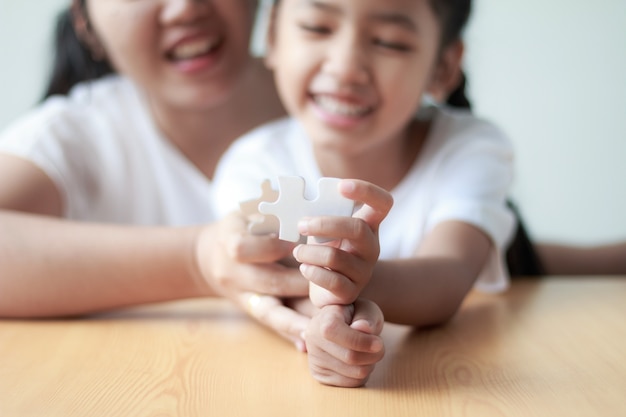 Bambina asiatica che gioca puzzle con sua madre per il concetto &quot;nucleo familiare&quot;