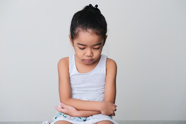 Bambina asiatica che mostra un'espressione triste quando è seduta con la faccia che guarda in basso