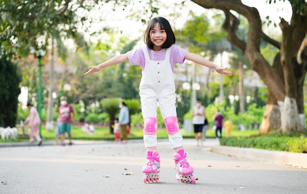 Bambina asiatica che pratica il pattinaggio a rotelle nel parco