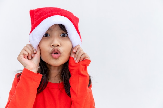 Bambina asiatica in cappello rosso della Santa su fondo bianco.