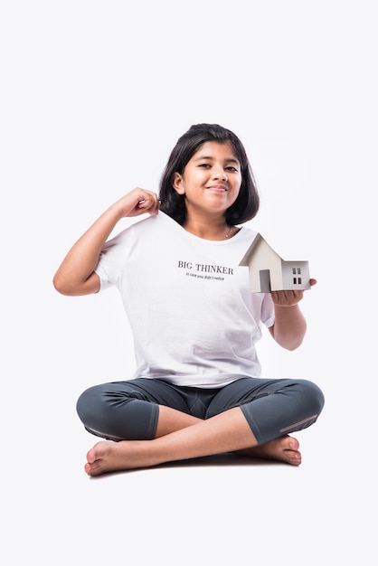 Bambina asiatica indiana che tiene il modello della casa di carta su sfondo bianco - concetto di casa e famiglia