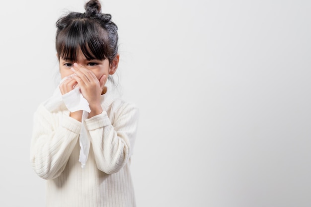 Bambina asiatica malata di starnuti sul naso e tosse fredda su carta velina perché debole o virus e batteri dovuti alla polvere