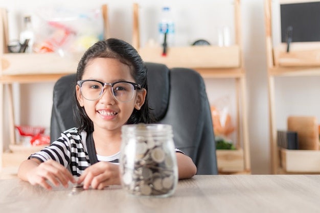 Bambina asiatica nel sorridere con la moneta