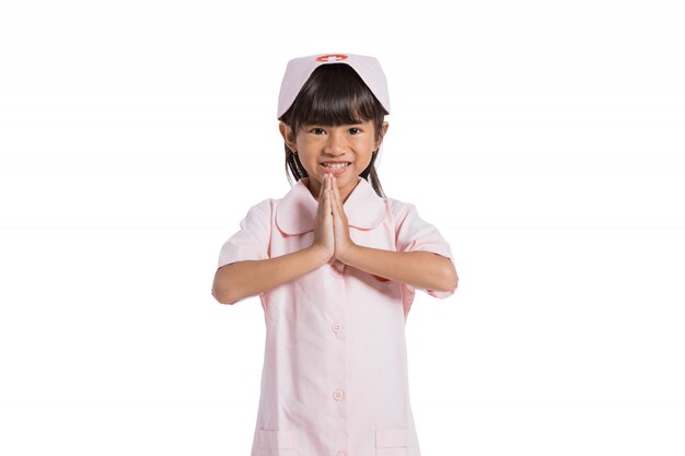 Bambina asiatica sveglia che indossa un'uniforme di medico