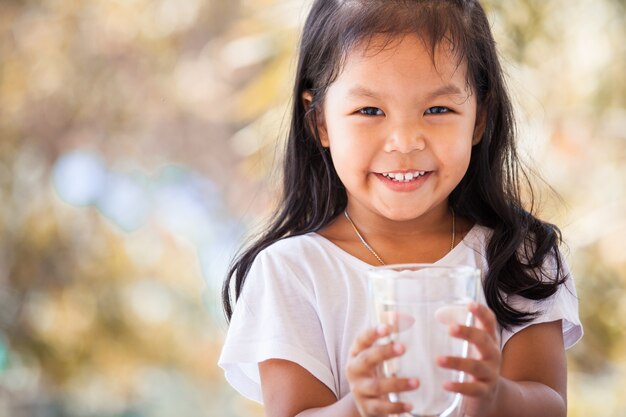 Bambina asiatica sveglia che tiene vetro di acqua dolce nel tono d&#39;annata di colore