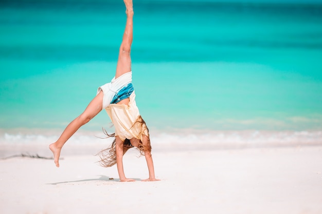 Bambina attiva in spiaggia divertendosi molto sulla riva facendo un salto