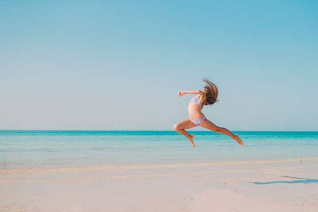 Bambina attiva sulla spiaggia divertendosi molto in acque poco profonde