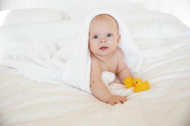 bambina avvolta in un asciugamano sdraiato in camera da letto dopo il bagno