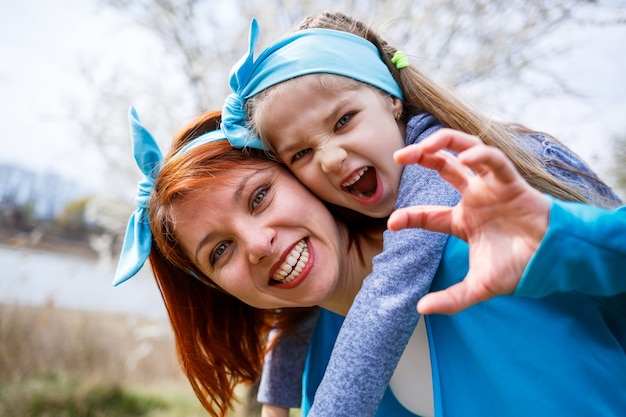 Bambina bambino e madre donna cammina attraverso la foresta primaverile con alberi in fiore, ridere e giocare, l'inizio della primavera, le vacanze in famiglia, l'amore dei genitori