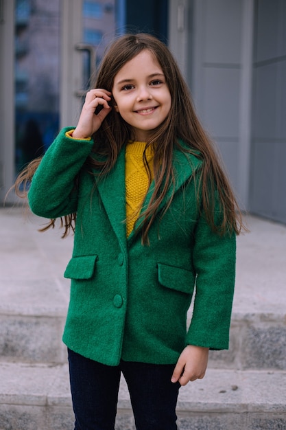 Bambina bambino in cappotto verde in posa