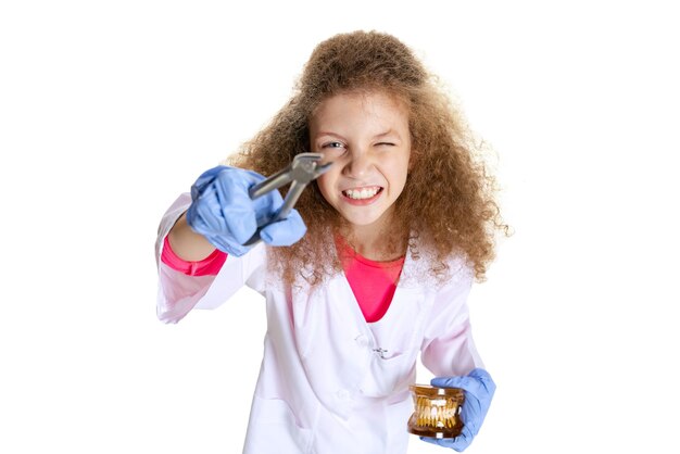 Bambina, bambino nell'immagine del dentista in camice bianco che tiene il dente isolato su sfondo bianco