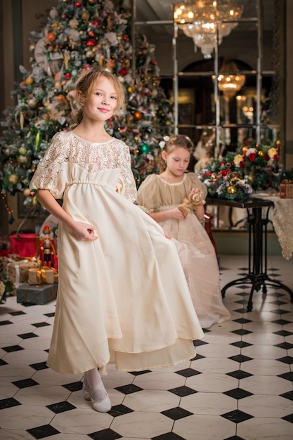 Bambina ben vestita a casa che balla intorno all'albero di Natale