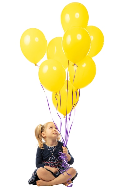 Bambina bionda caucasica con palloncini gialli isolati su bianco.