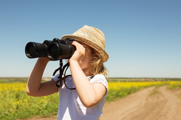 Bambina bionda che guarda attraverso il binocolo