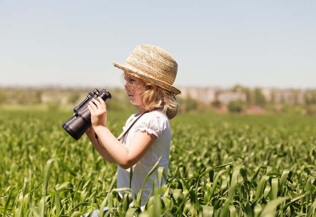 Bambina bionda che guarda attraverso il binocolo