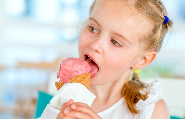 Bambina bionda che mangia gustoso gelato rosa