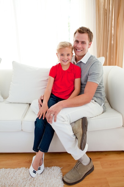 Bambina bionda che si siede sul divano con suo padre