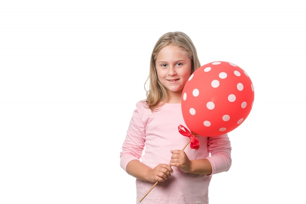 Bambina bionda che sorride alla macchina fotografica con un pallone