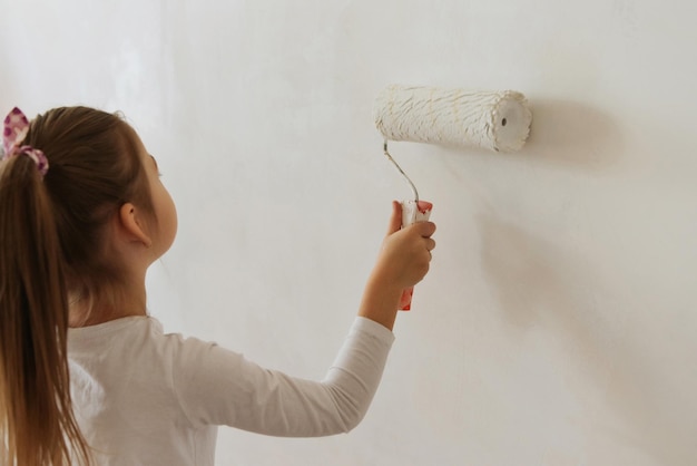 bambina bionda con rullo di pittura murale durante la ristrutturazione domestica